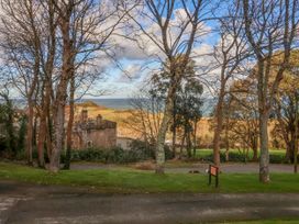 Trees with a view of a stone building and sea in the background at Cove View in Ilfracombe