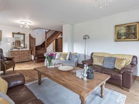 A living room with leather sofas wooden coffee table flowers on table and staircase at Cilfan in Llanrwst