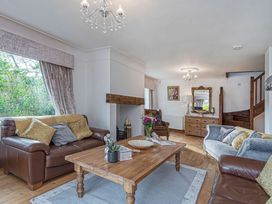 A living room with two sofas a wooden coffee table a wooden chest of drawers a mirror a chair and a staircase at Cilfan in Llanrwst