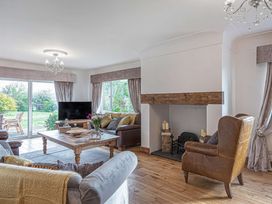 A living room with sofas a wooden coffee table a fireplace and large windows at Cilfan in Llanrwst