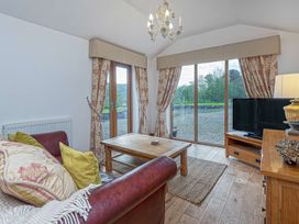 A living room with a leather sofa wooden coffee table television and large windows at Cilfan in Llanrwst