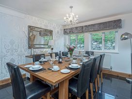 A dining room with a wooden table set for a meal and black chairs at Cilfan in Llanrwst
