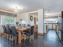 A dining area with a table set for eight and a kitchen with cabinets and appliances at Cilfan in Llanrwst