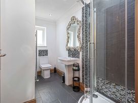 A bathroom with a toilet sink mirror and a shower at Cilfan in Llanrwst