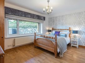 A bedroom with a wooden bed and patterned wallpaper at Cilfan in Llanrwst