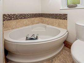 A corner bathtub with a faucet beside a toilet in a bathroom at Cilfan in Llanrwst