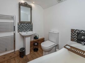 A bathroom with a pedestal sink mirror toilet bathtub and towel warmer at Cilfan in Llanrwst