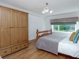 A bedroom with a wooden bed and wardrobe and a window with a patterned blind at Cilfan in Llanrwst