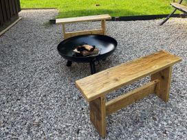 An outdoor area with a fire pit and wooden benches at Fig Tree Lodge in Hutton Roof near Penrith