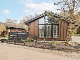 A wooden cabin with large windows and a path at Fig Tree Lodge in Hutton Roof near Penrith
