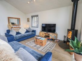A living room with a sofa, television, and fireplace at Fig Tree Lodge in Hutton Roof near Penrith