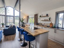 A kitchen and dining area with bar stools and a dining table at Fig Tree Lodge in Hutton Roof near Penrith