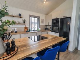A kitchen with an island and bar stools at Fig Tree Lodge Hutton Roof near Penrith