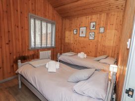 A bedroom with two beds and pictures on the wall at Fig Tree Lodge Hutton Roof near Penrith