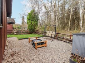 A garden with gravel, a swing seat, and a bench at Fig Tree Lodge in Hutton Roof near Penrith
