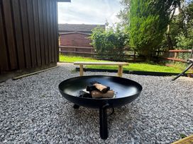 An outdoor area with a fire pit and wooden bench at Fig Tree Lodge Hutton Roof near Penrith