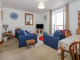 A living room with blue sofas a TV and a dining table at Captain's Rest in Porthmadog