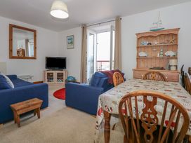 A living room with blue sofas a wooden dining table with chairs and a wooden cabinet with nautical decorations at Captains Rest in Porthmadog