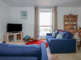 A living room with blue sofas tv on a wooden cabinet and a wooden cupboard with nautical decorations at Captain's Rest in Porthmadog