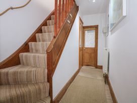 A hallway with a carpeted staircase wooden door and radiator at Captains Rest in Porthmadog