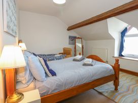 A bedroom with two single beds a standing mirror and a window with blue curtains at Captain's Rest in Porthmadog