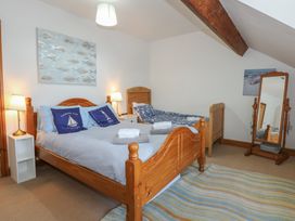 A bedroom with two wooden beds a mirror on a stand a wall painting and two bedside lamps at Captain's Rest in Porthmadog