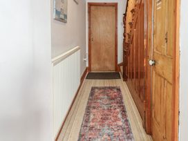 A hallway with a patterned runner rug a radiator wooden doors and a staircase at Captain's Rest in Porthmadog