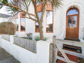 Front exterior of a white house with large windows wooden door small garden and wooden gate at Mermaid's Rest in Newquay