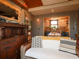 A living room with a leather sofa and cushions facing a dining area with a wooden table and chairs at Mermaid's Rest in Newquay