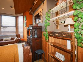A living room with brown sofas wooden shelving and a decorative mirror at Mermaid's Rest in Newquay
