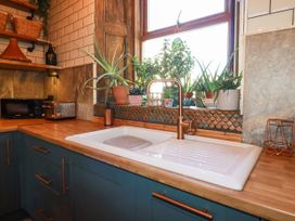 A kitchen sink with a bronze faucet and plants on the windowsill at Mermaid's Rest in Newquay