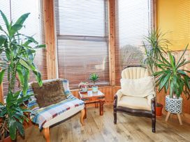 A sitting area with two armchairs a small wooden table and several potted plants at Mermaid's Rest in Newquay