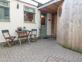 An outdoor patio area with a small table and two chairs next to a door and wooden fence at The Aqua Shack in Newquay