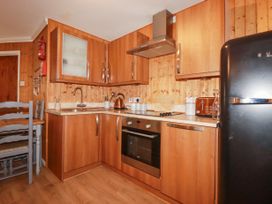 A kitchen with wooden cabinets appliances and a dining table at The Aqua Shack in Newquay