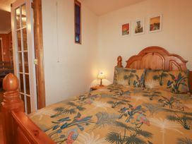 A bedroom with a wooden bed frame floral bedding and three framed pictures on the wall at The Aqua Shack in Newquay