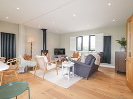 A living room with multiple chairs a sofa a wood burning stove and a TV at Holm Oaks Cottage in Busbridge near Godalming