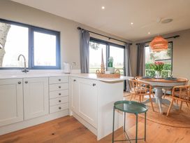 A kitchen with white cabinets and a dining area with a round table and four chairs at Holm Oaks Cottage in Busbridge near Godalming