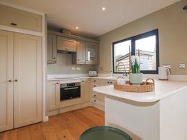 A kitchen with beige cabinets a countertop a window and a basket with flowers at Holm Oaks Cottage in Busbridge near Godalming