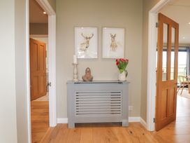 A hallway with a radiator cover holding a candle holder statue and vase of flowers at Holm Oaks Cottage Busbridge near Godalming