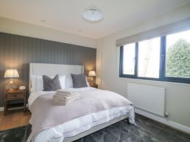 A bedroom with a double bed two bedside tables lamps folded towels on the bed and a large window at Holm Oaks Cottage in Busbridge near Godalming
