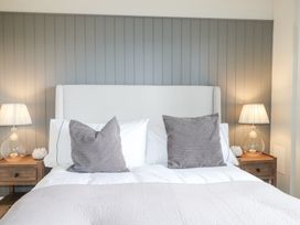 A bedroom with a bed with gray and white pillows and two bedside tables with lamps at Holm Oaks Cottage in Busbridge near Godalming