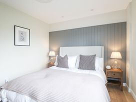 A bedroom with a double bed two grey pillows wooden bedside tables and lamps at Holm Oaks Cottage in Busbridge near Godalming