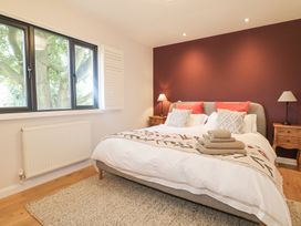 A bedroom with a double bed two bedside tables with lamps and a window showing a tree at Holm Oaks Cottage in Busbridge near Godalming