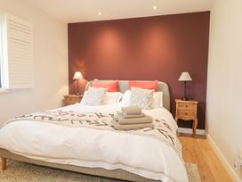 A bedroom with a bed between two wooden nightstands with lamps at Holm Oaks Cottage in Busbridge near Godalming