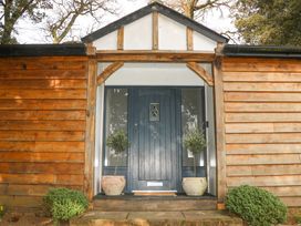 A wooden exterior entrance with a dark blue door and potted plants at Holm Oaks Cottage in Busbridge near Godalming