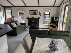 A living room with two sofas, a TV, and a fireplace at 2 Riverside Lodge Abercych near Cenarth