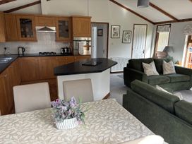 A kitchen and living room area with dining table and sofa at 2 Riverside Lodge Abercych near Cenarth