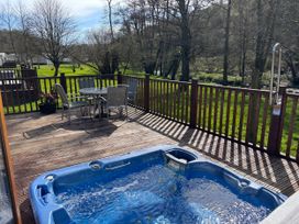 An outdoor area with a hot tub and seating at 2 Riverside Lodge Abercych near Cenarth