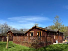 Wooden lodges with decking in a garden at 2 Riverside Lodge Abercych near Cenarth