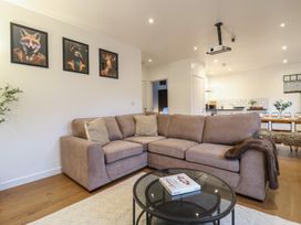 A living room with a beige corner sofa, a glass coffee table, three animal portraits on the wall at Hub House in Three Oaks near Hastings